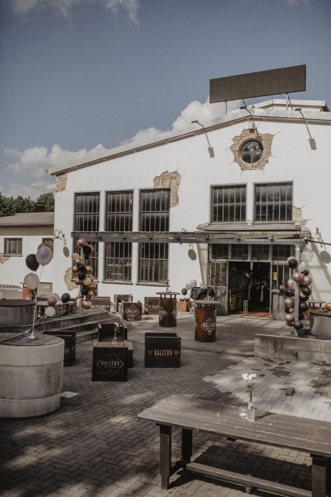 Außenansicht der Hochzeitslocation im Industriestil – weiße Fassade mit Ballondeko