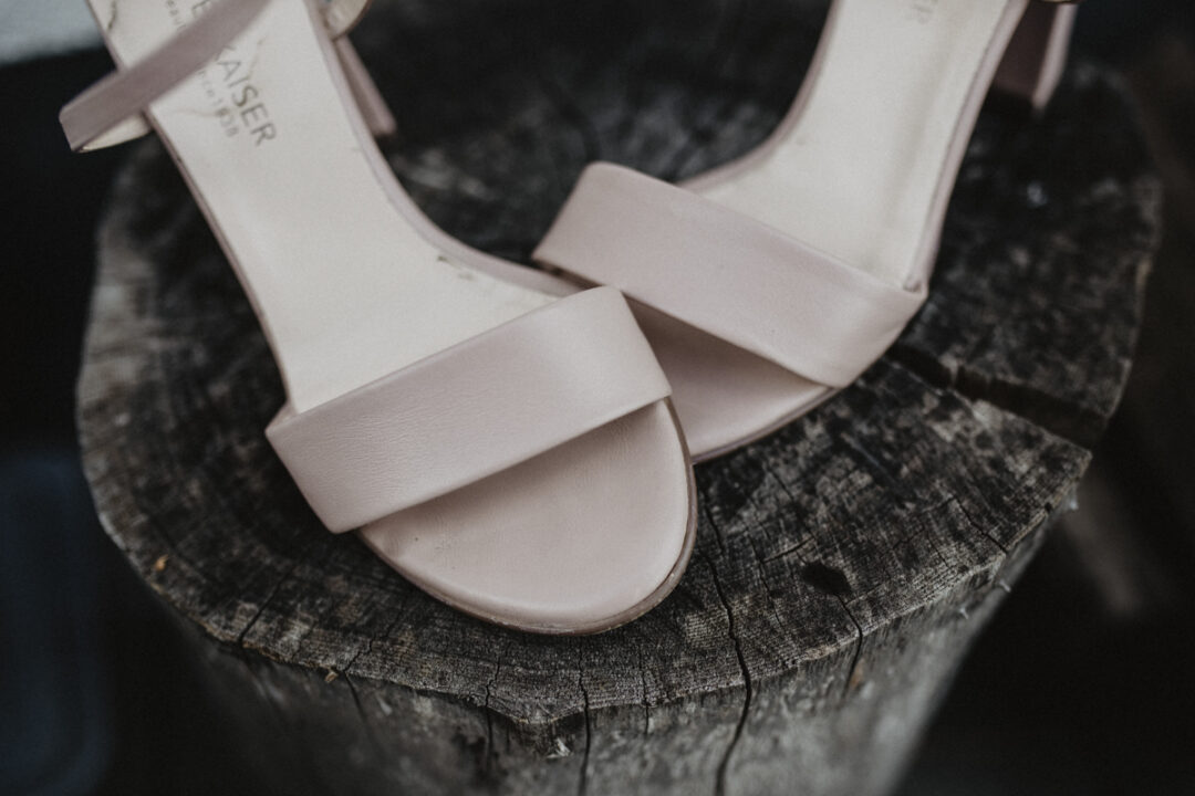 Nude-farbene Brautschuhe auf rustikalem Holzstamm – harmonischer Stilbruch