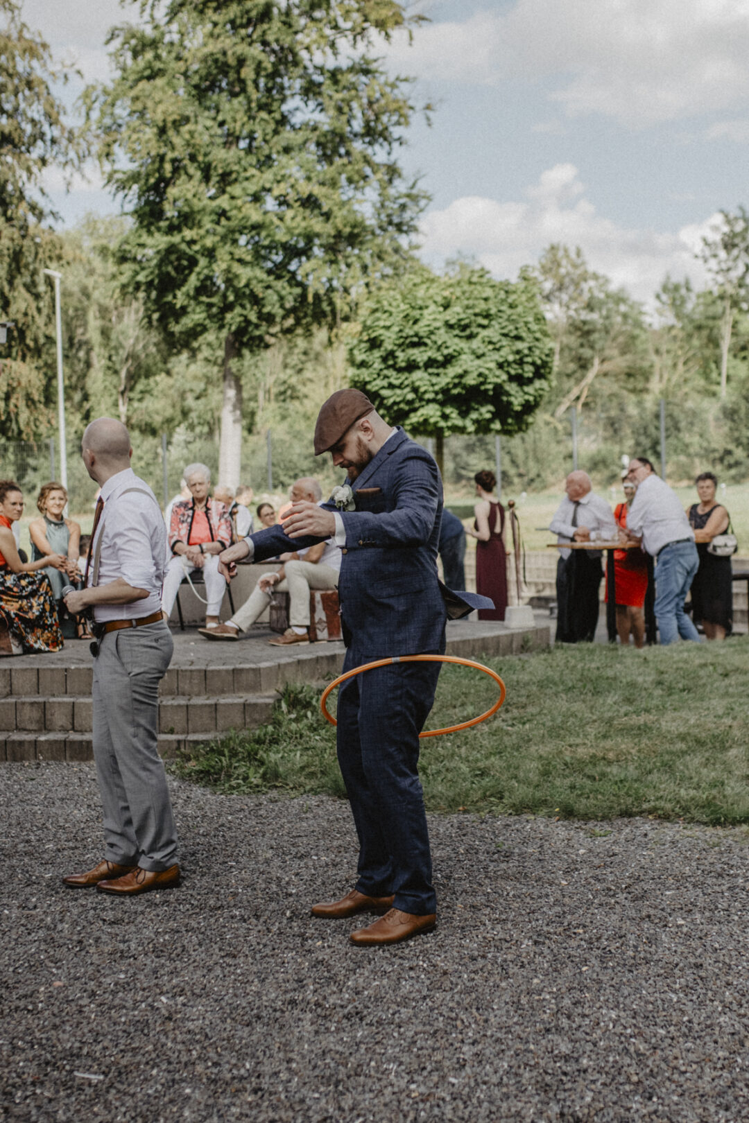 Bräutigam spielt mit Hula-Hoop-Reifen, während Gäste entspannt im Hintergrund sitzen