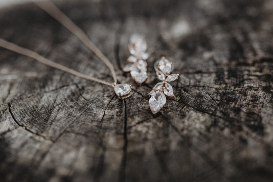 Hochzeitskette und Ohrringe auf Holz – feine Details im Kontrast zur Kulisse