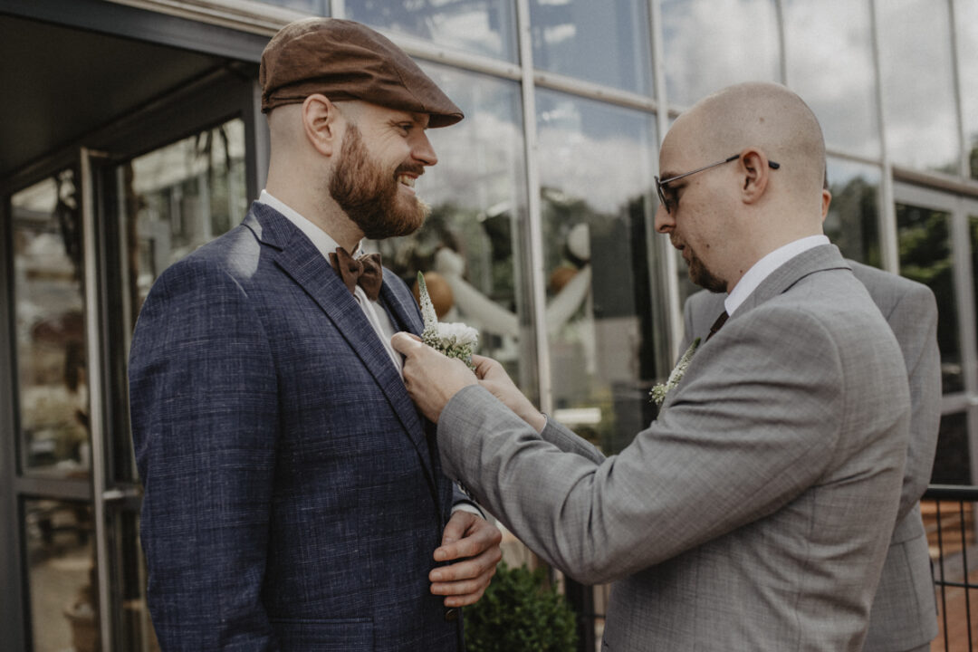 Trauzeuge hilft beim Anstecken der Blume – stilvoller Hochzeitsmoment im Sauerland