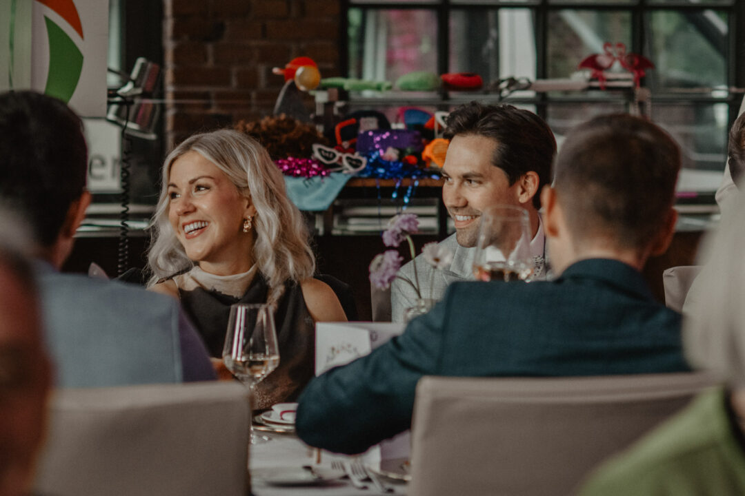 Hochzeitsgäste lachen während der Rede im Saal