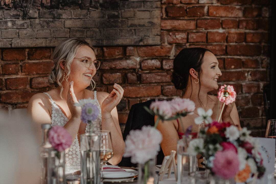 Braut und Freundin klatschen und lächeln bei Tisch