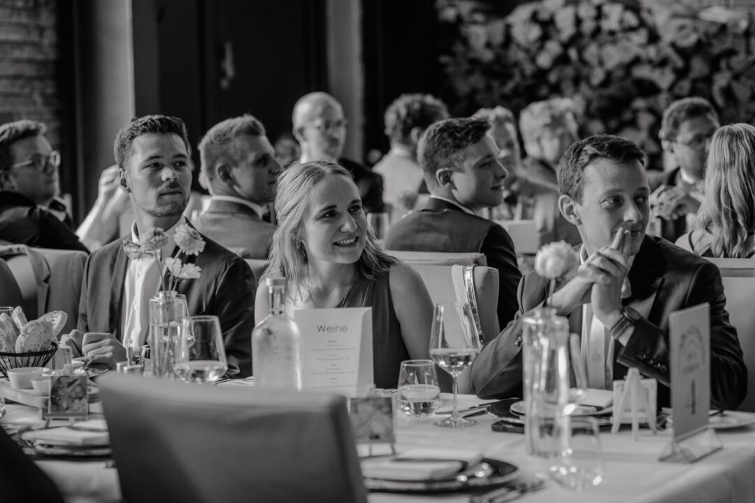 Gäste hören gespannt zu und genießen ihr Glas Wein