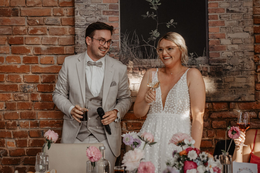 Brautpaar mit Mikrofon und Wein während der Hochzeitsrede