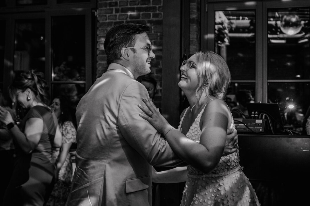 Brautpaar tanzt lachend in Schwarzweißaufnahme