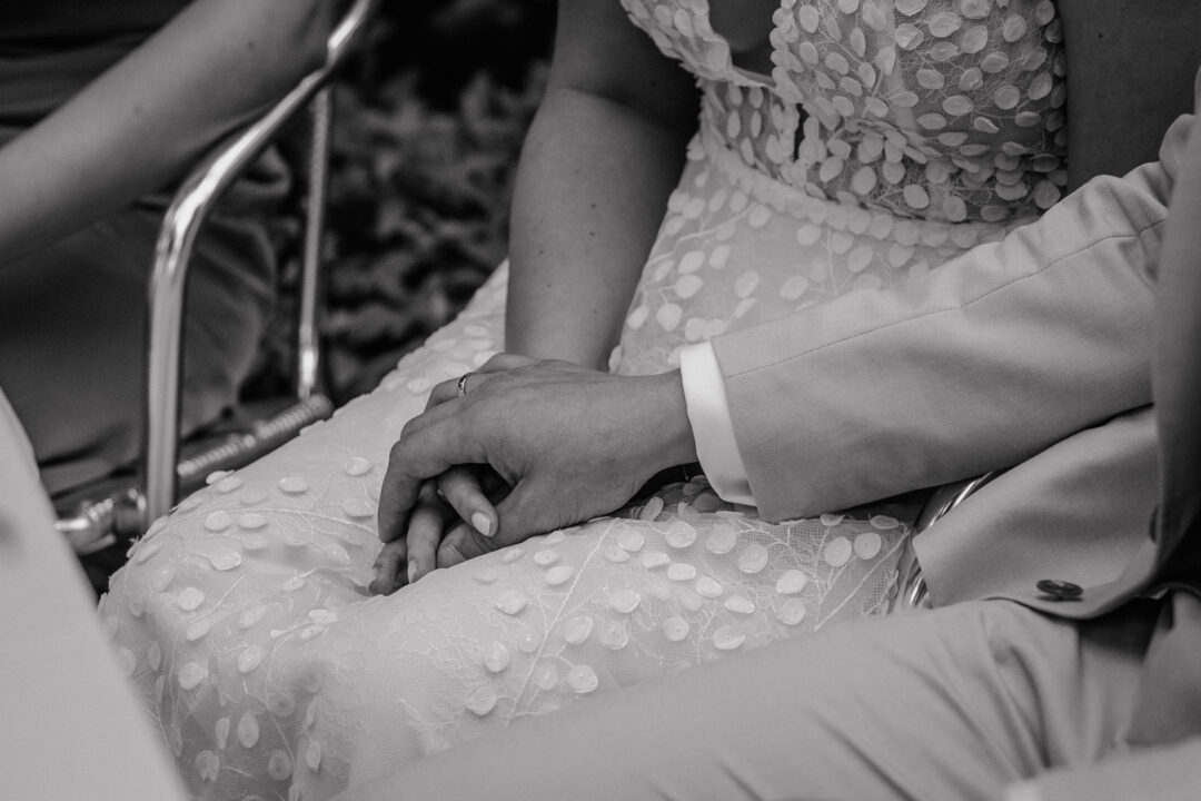 Nahaufnahme der Hände mit Eheringen im Hochzeitskleid