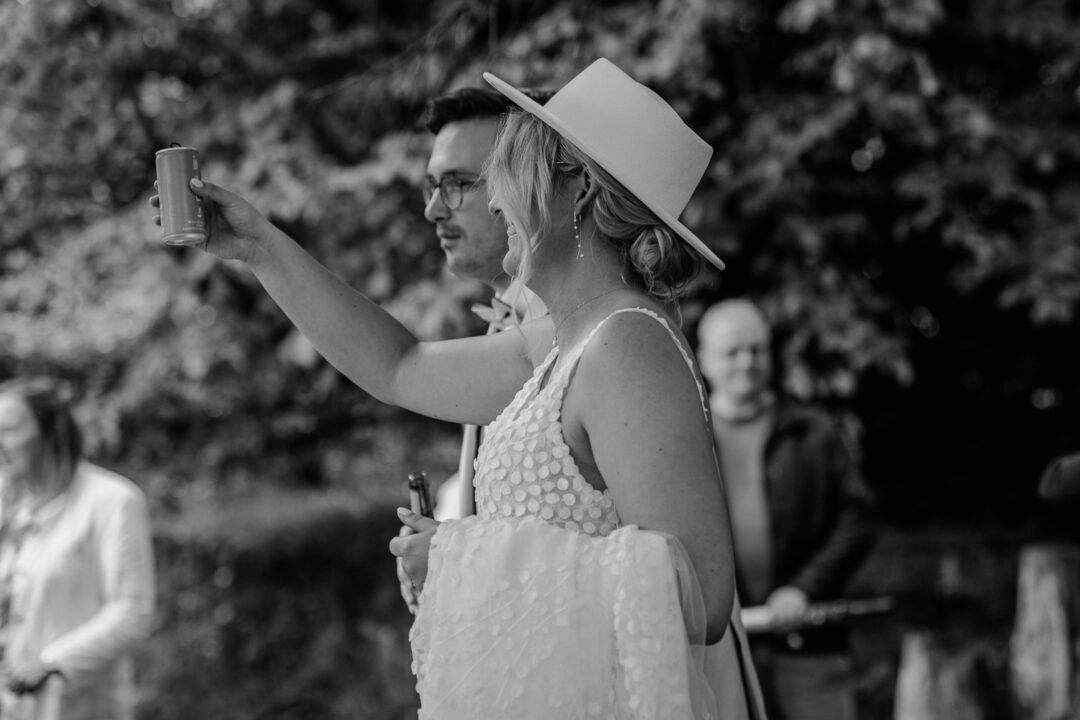 Braut hebt Getränk zum Anstoßen im Botanischen Garten Osnabrück