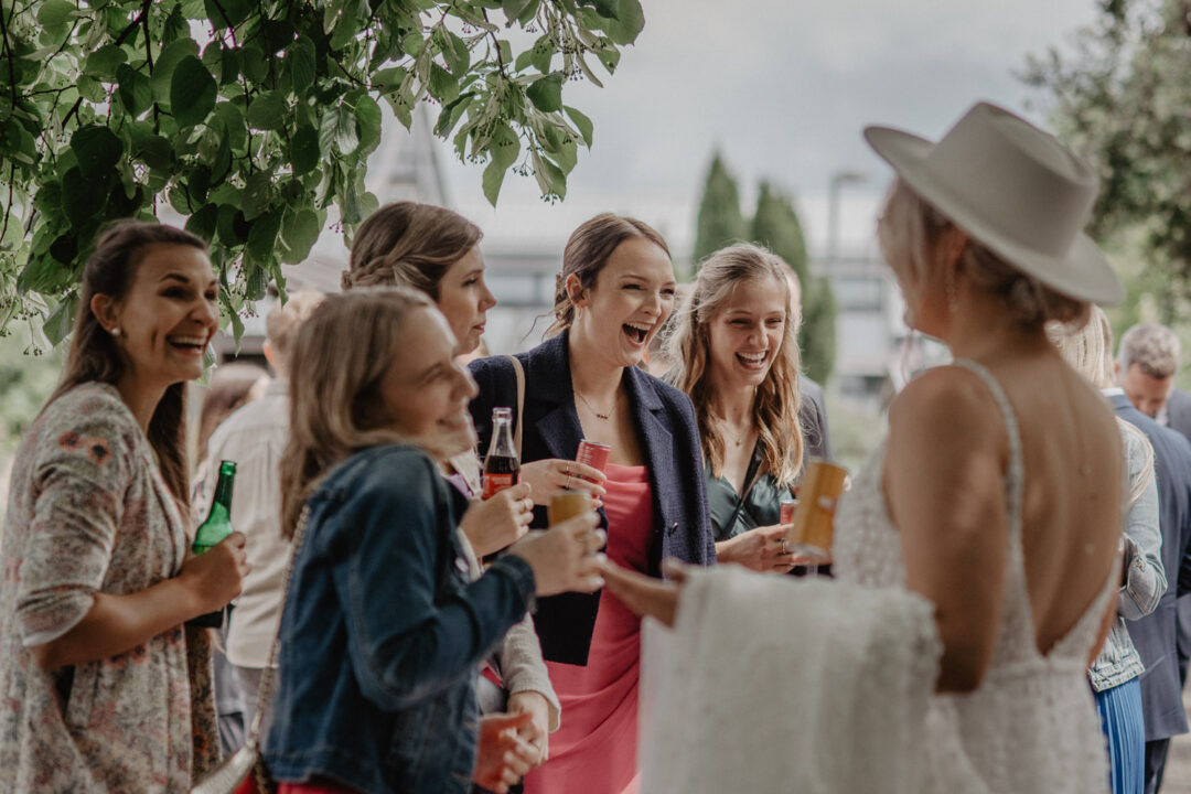 Braut spricht mit fröhlichen Gästen beim Sektempfang