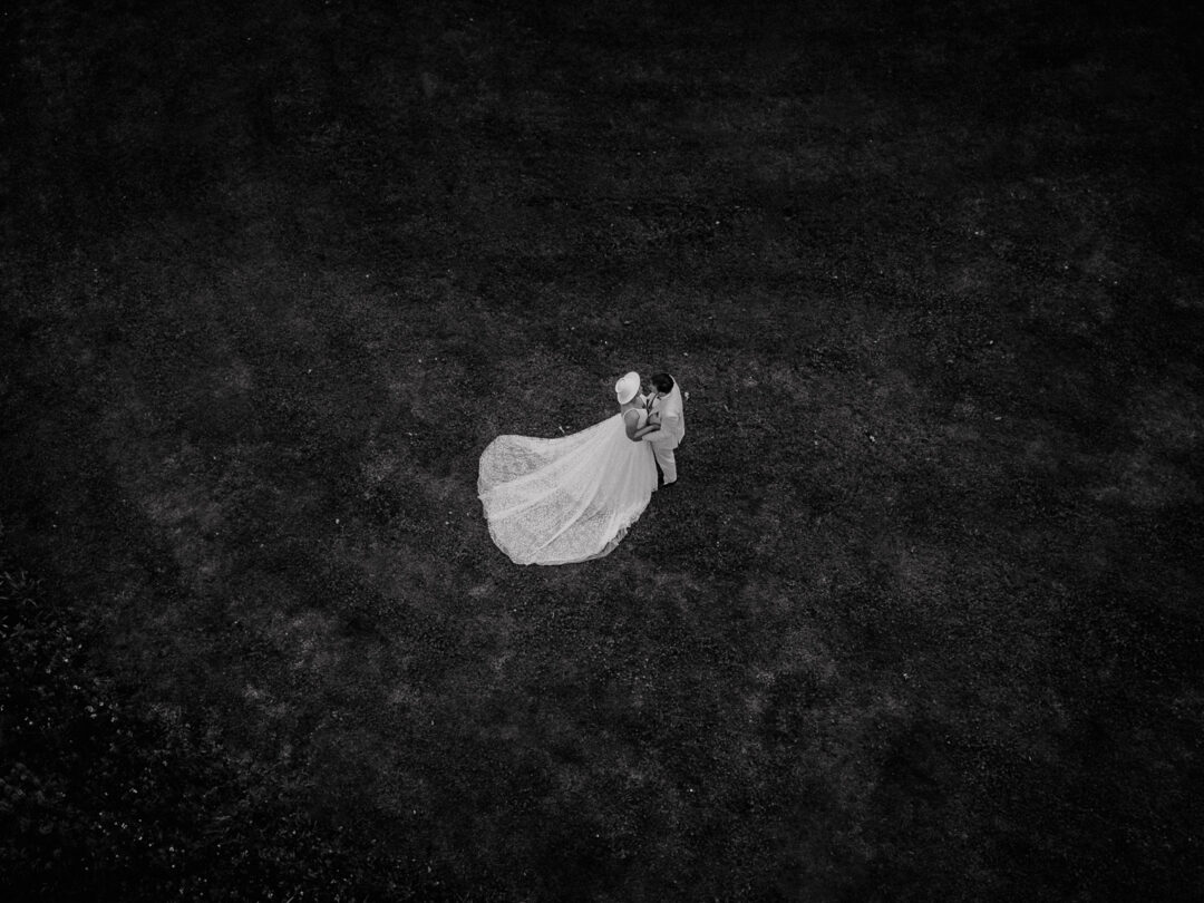 Brautpaar umarmt sich auf Wiese aus der Vogelperspektive