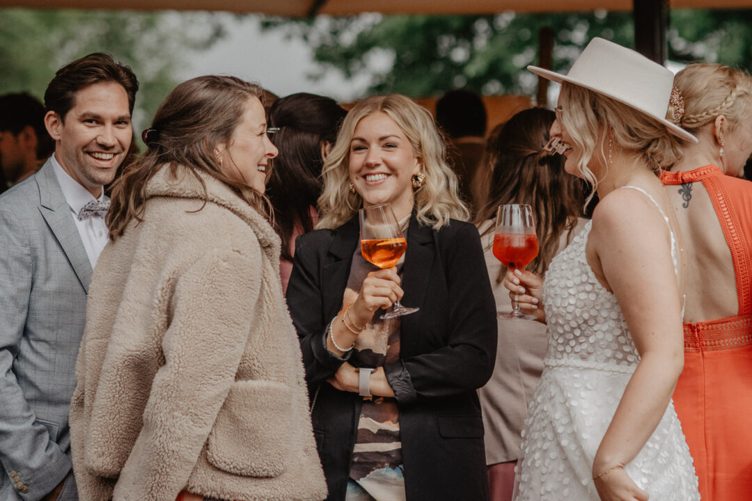 Braut stößt lachend mit Freundinnen beim Empfang an