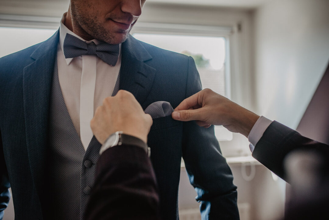 Detailaufnahme vom Bräutigam im Anzug und Fliege beim Getting Ready.