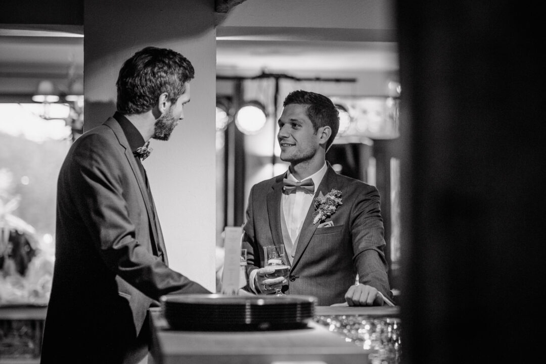 Bräutigam unterhält sich an der Bar mit einem Freund, Schwarz-Weiß Aufnahme.