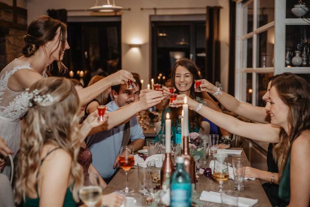 Braut stößt lachend mit Freundinnen bei der Feier an.