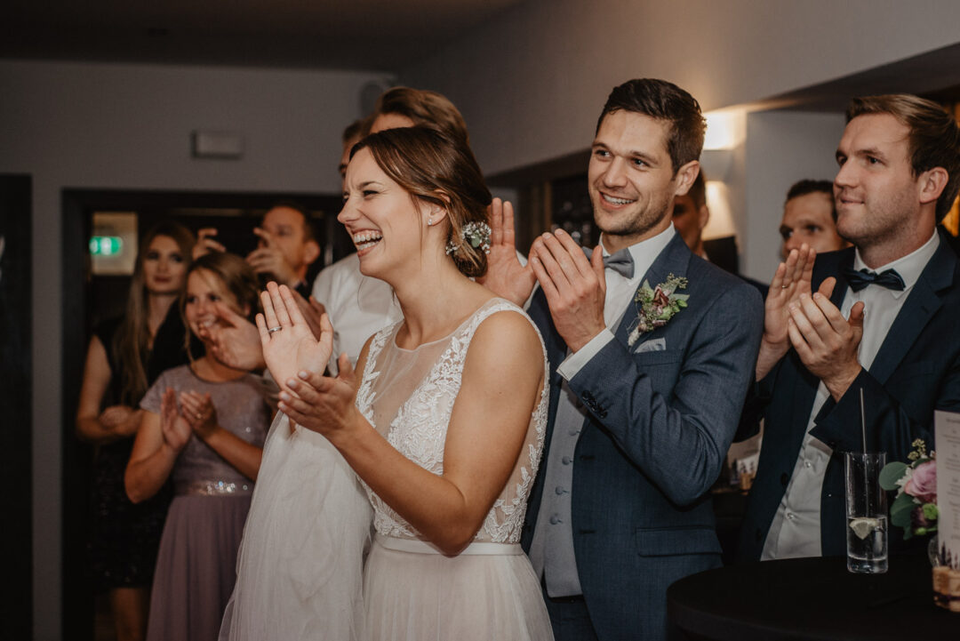 Brautpaar klatscht gemeinsam mit Gästen während der Feier.