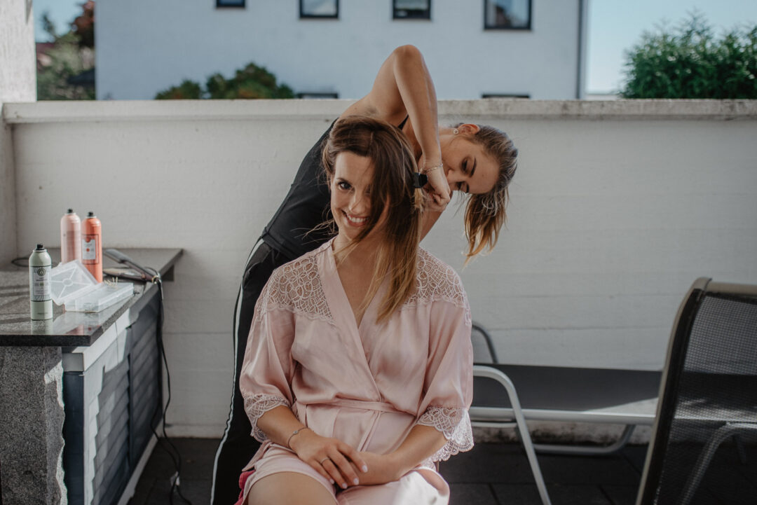 Braut wird beim Getting Ready von der Stylistin frisiert.