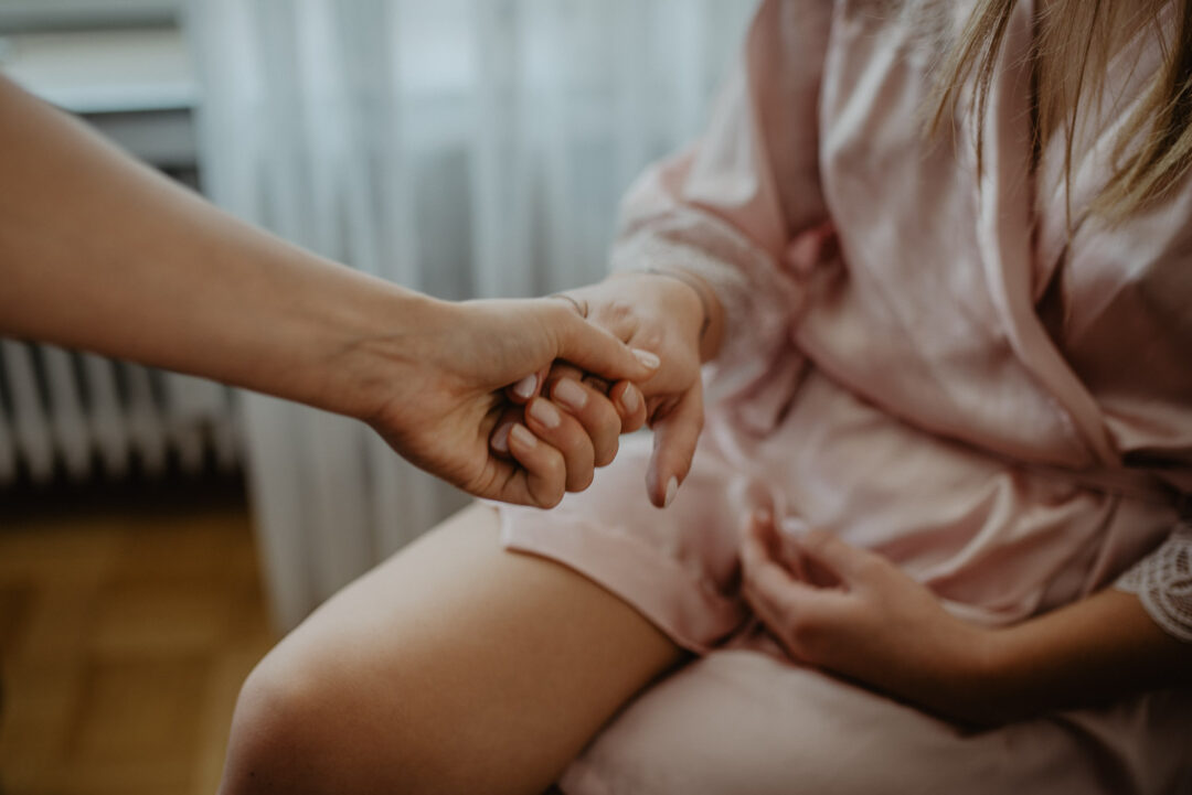 Hände halten sich während des Getting Ready der Braut.