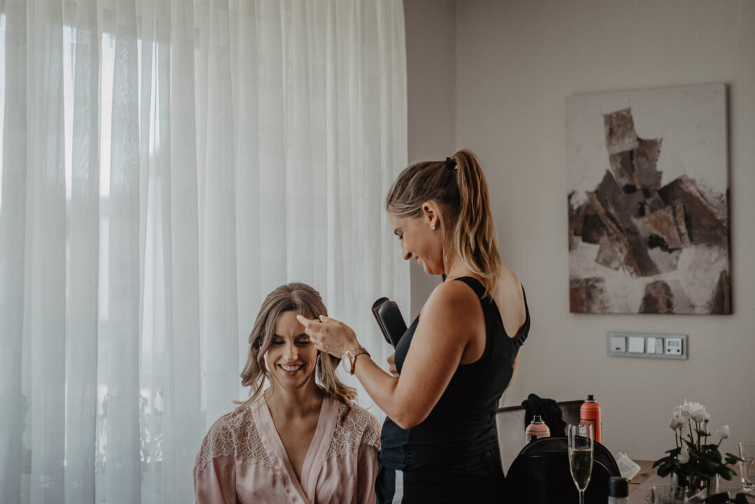Braut beim Haarstyling durch die Stylistin während des Getting Ready.