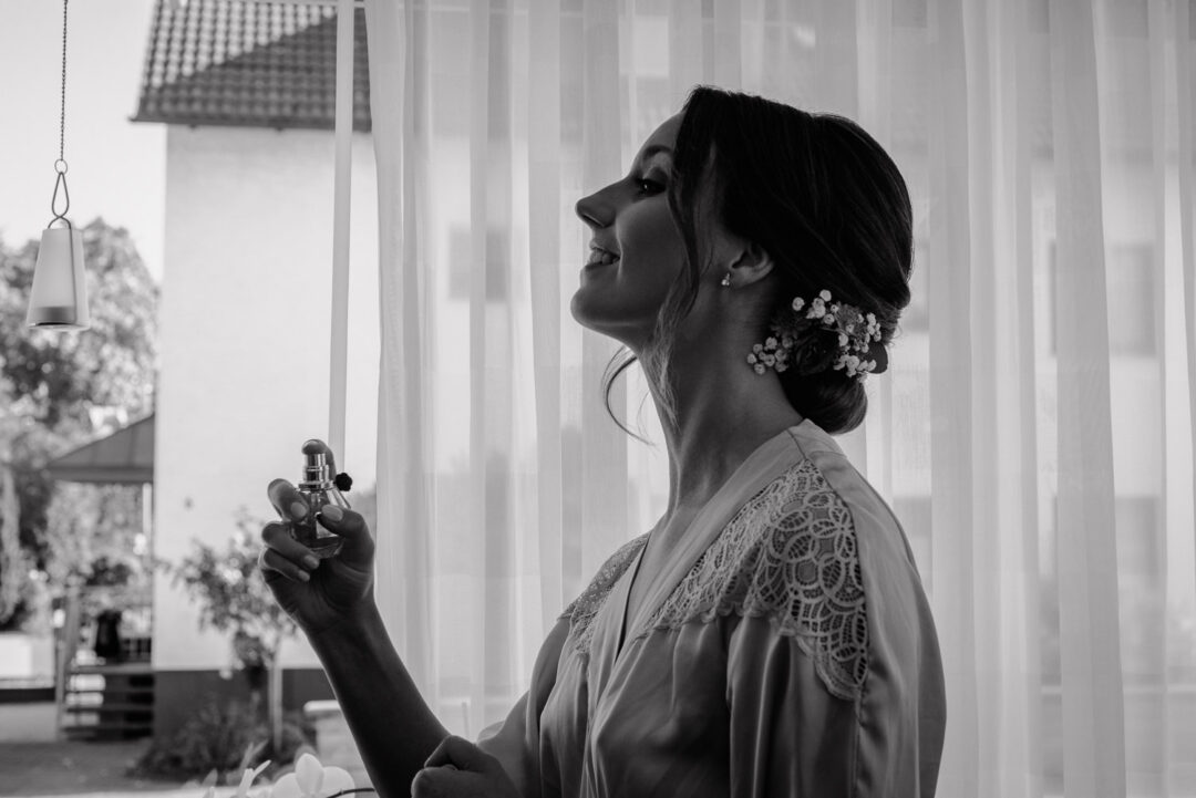 Braut sprüht Parfum auf, Schwarz-Weiß Aufnahme beim Getting Ready.