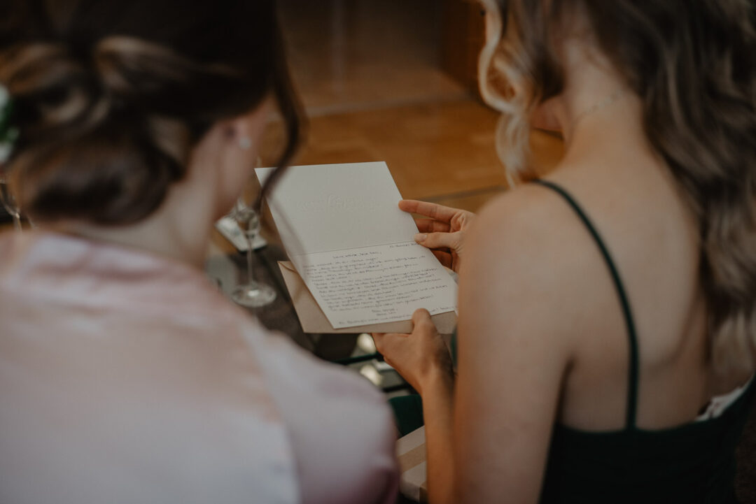 Brautjungfer liest eine Karte beim Getting Ready zusammen mit der Braut.