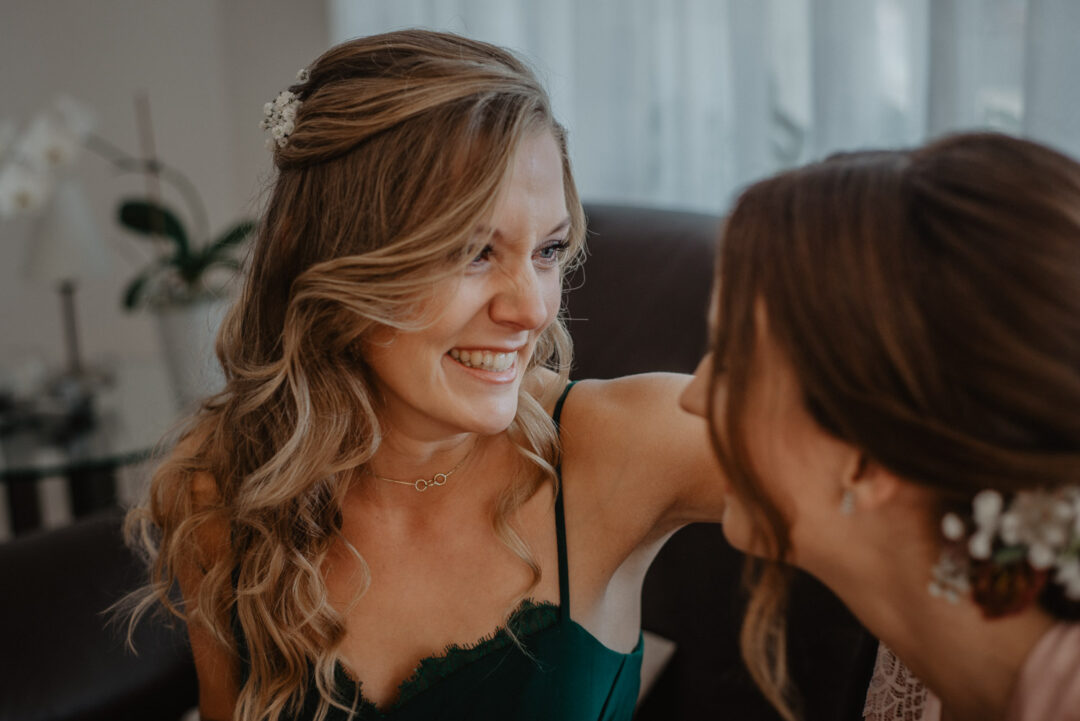 Brautjungfer lächelt die Braut liebevoll beim Getting Ready an.