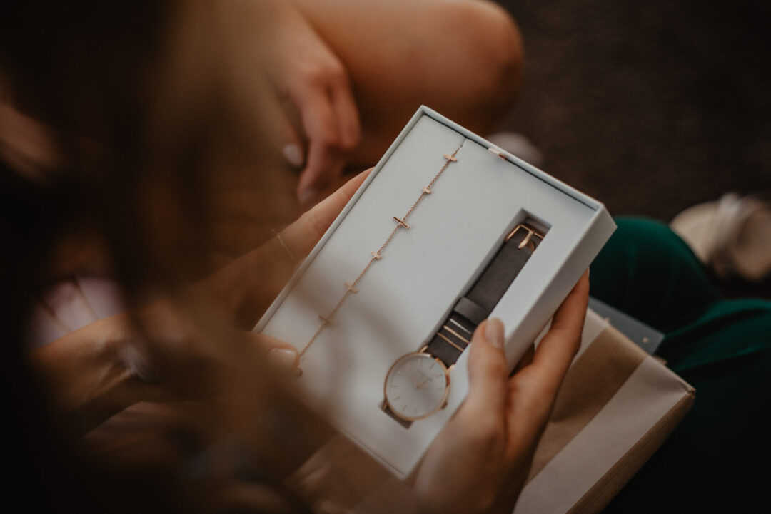 Brautjungfer hält ein Geschenkset mit Uhr und Armband in den Händen.