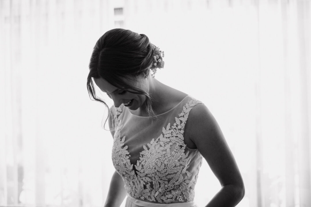 Braut lächelt in ihrem Hochzeitskleid beim Getting Ready, Schwarz-Weiß.