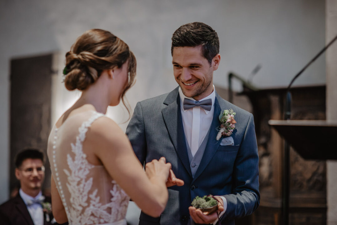 Bräutigam steckt der Braut während der kirchlichen Trauung den Ring an.