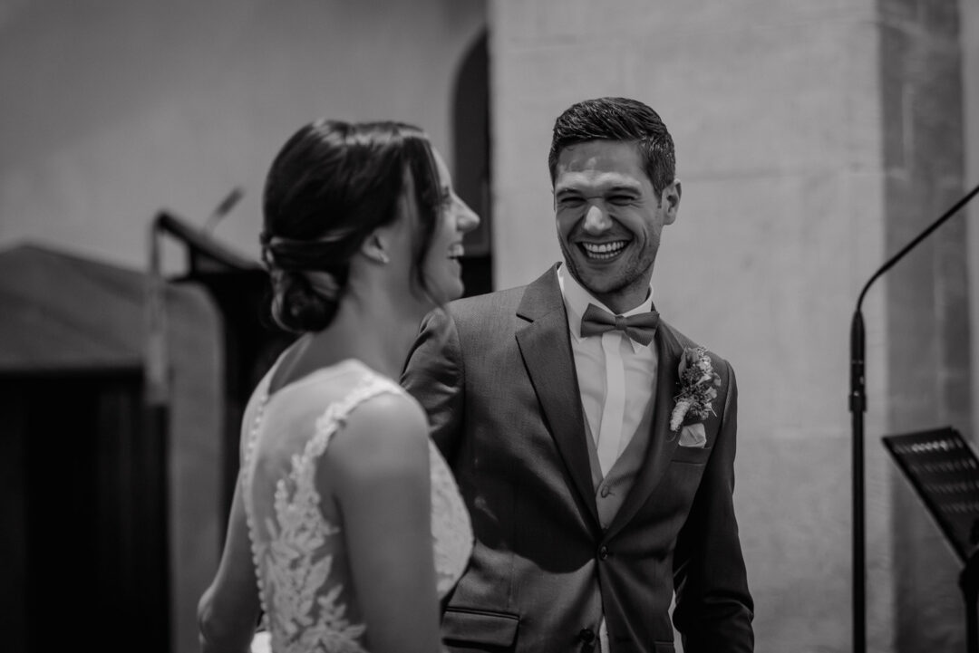 Braut und Bräutigam lachen sich während der Trauung an, Schwarz-Weiß Aufnahme.