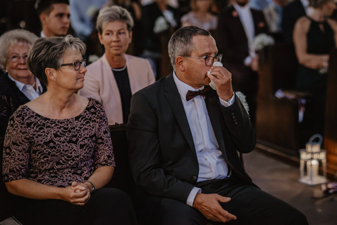 Vater wischt sich während der Zeremonie die Tränen, Mutter sitzt daneben.