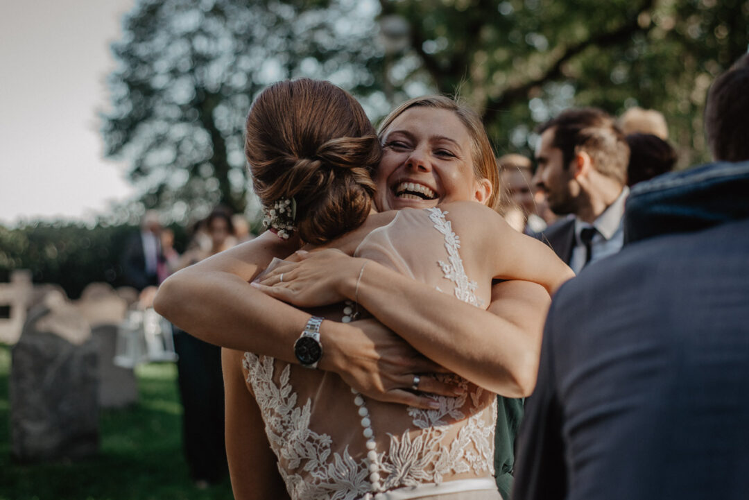 Braut umarmt eine weitere Freundin voller Freude nach der Trauung.