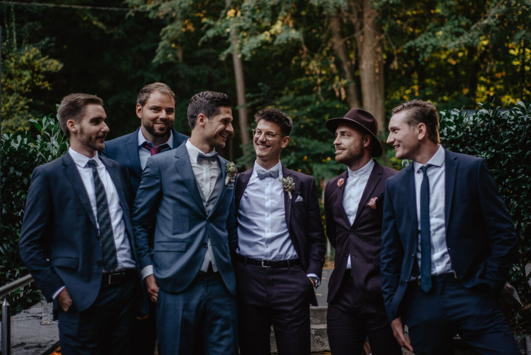 Bräutigam steht mit seinen Freunden lachend vor dem Wirtshaus Krämer.