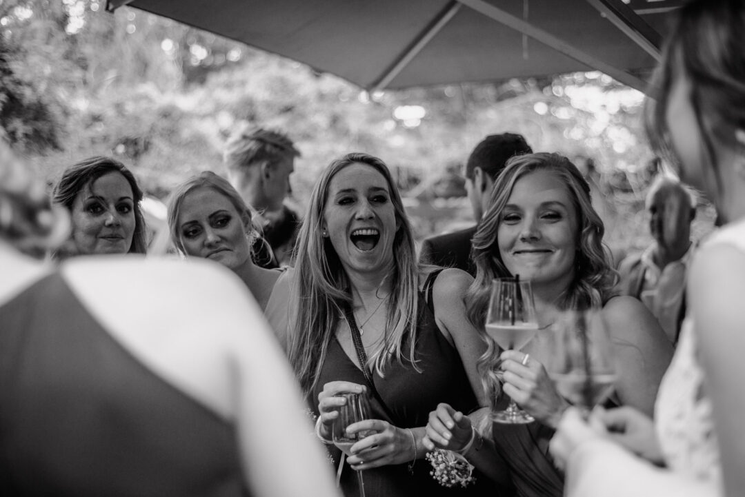 Freundinnen lachen herzlich während des Empfangs, Schwarz-Weiß Aufnahme.