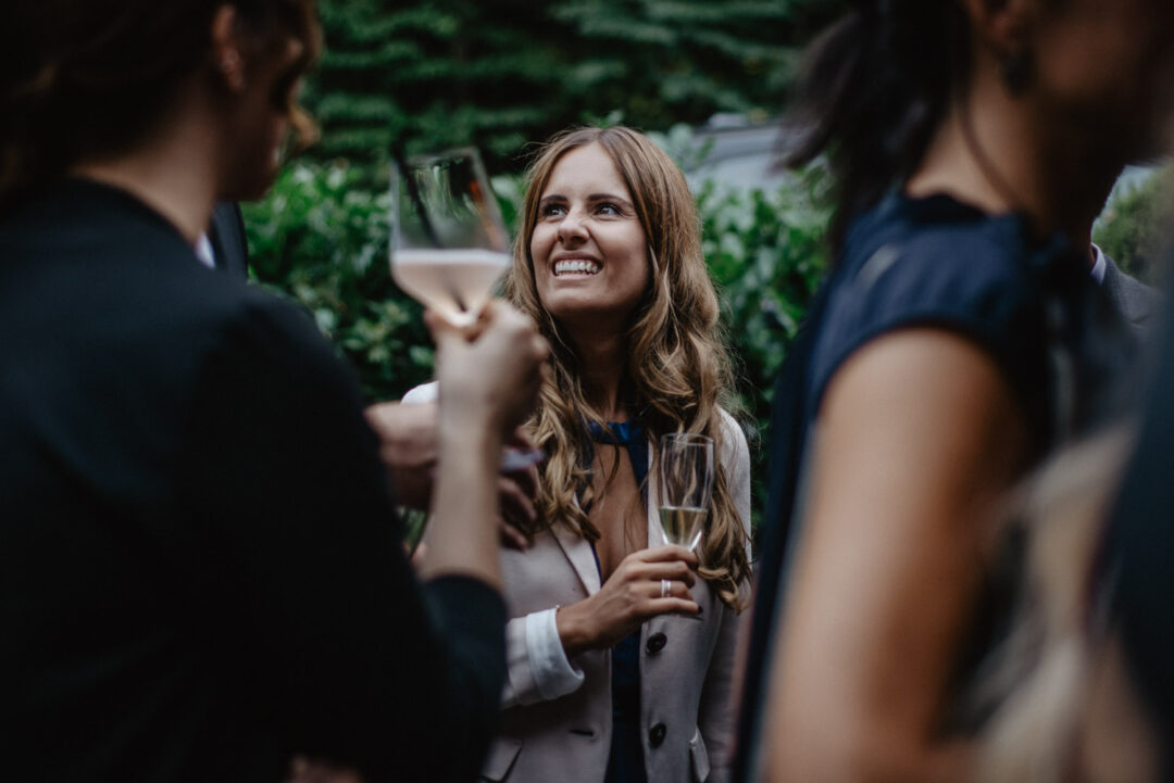 Junge Frau lächelt mit Glas Sekt beim Empfang im Wirtshaus Krämer.